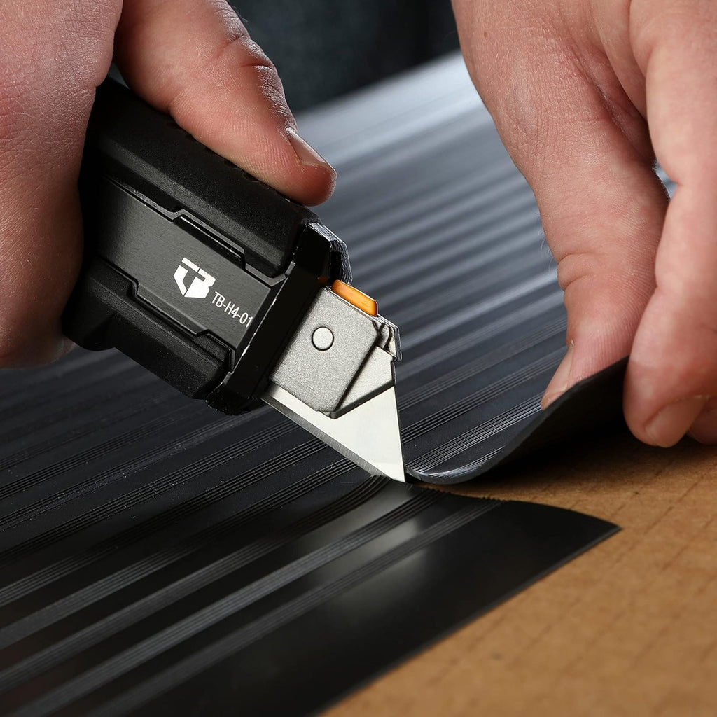 Precision cutting a heavy-duty black rubber sheet on cardboard using the utility knife tip.