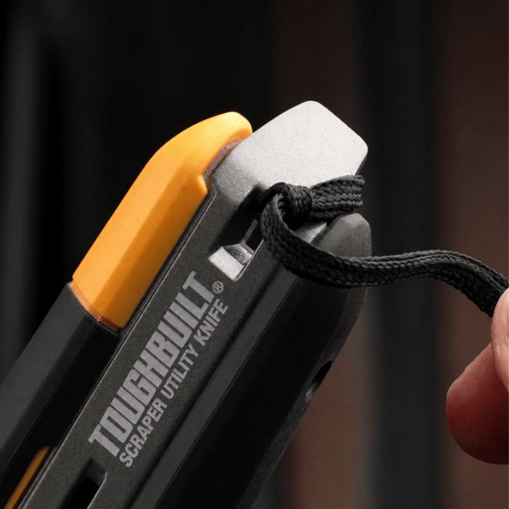 Close-up view of the integrated lanyard hole at the end of the knife handle with a black cord threaded through.